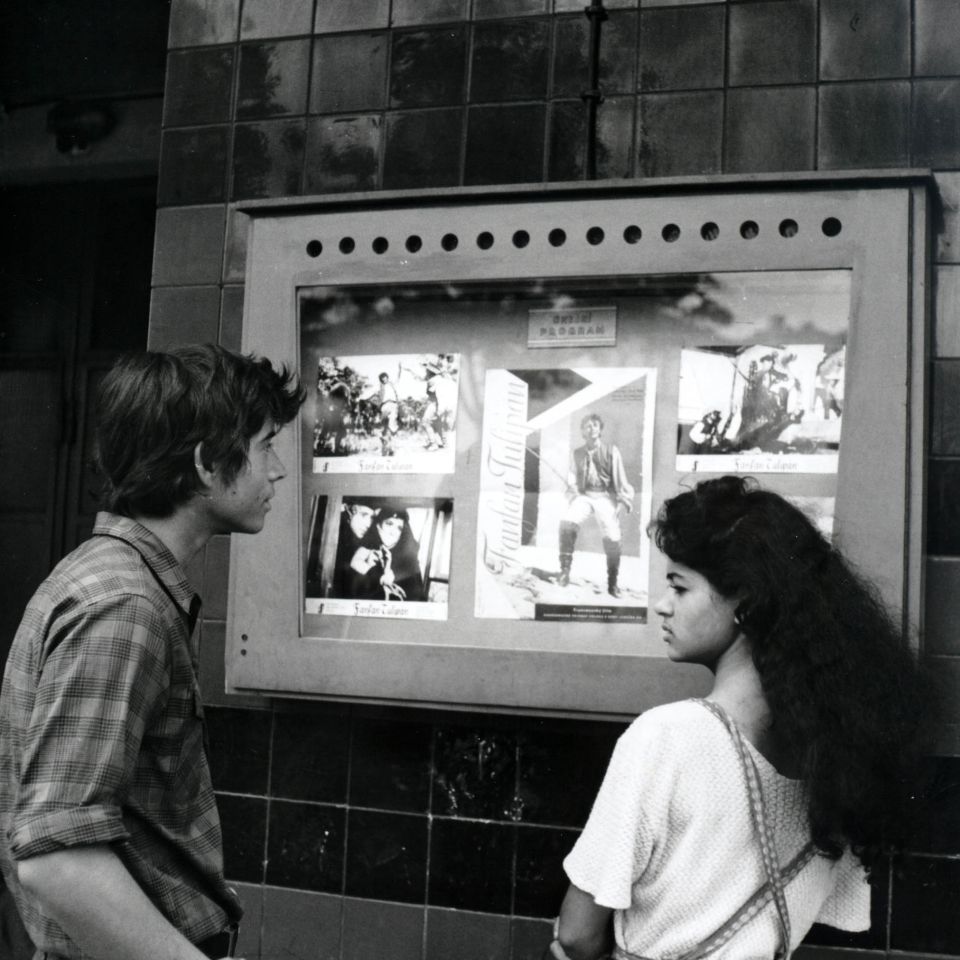 A young couple checking out the promotional material at a cinema in Pearls of the Deep